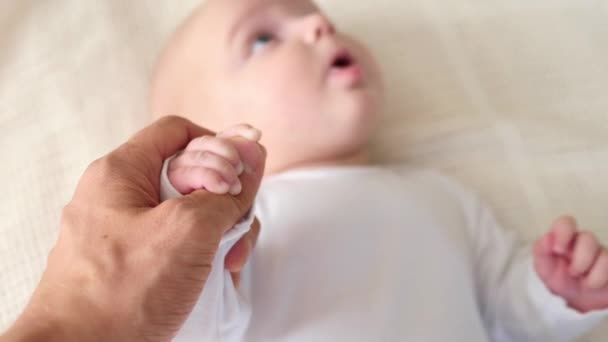 小さい赤ん坊の手を持っている父の手。クローズアップ. — ストック動画