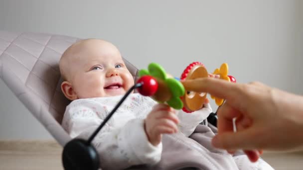 Schattig babymeisje zittend in uitsmijter en spelen met kleurrijke speelgoed — Stockvideo