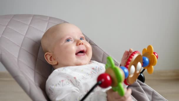 Glimlachende baby liggend in de stuiter Rocker met educatief speelgoed. — Stockvideo