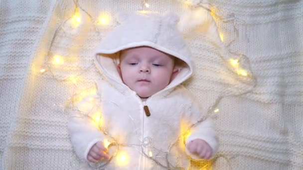 Schattig baby jongetje in sprankelende lichtjes decoraties. Bovenaanzicht. — Stockvideo