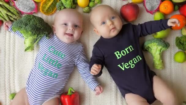 Baby tvillingar Född Veganska liggande i färska grönsaker och frukter. — Stockvideo