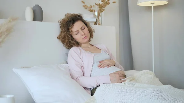 Ung upprörd gravid kvinna känner sig sjuk på sängen — Stockfoto