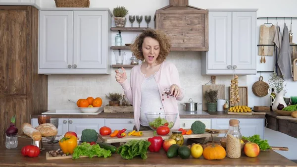 Glad gravid kvinna i köket gör hälsosam sallad. — Stockfoto