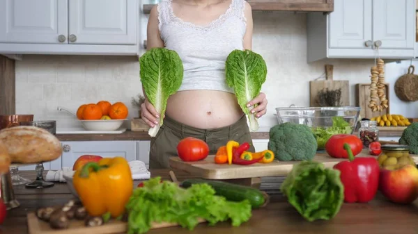 Gravid kvinna som håller gröna blad medan matlagning sallad hemma. Hälsosam graviditet koncept. — Stockfoto