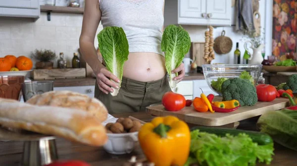 Närbild av mage av gravida kvinna med grön sallad. Hälsosam kost under graviditet. — Stockfoto