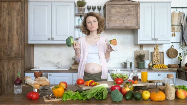 Terhes nő gondolkodás, mit együnk - Burger vagy brokkoli — Stock Fotó