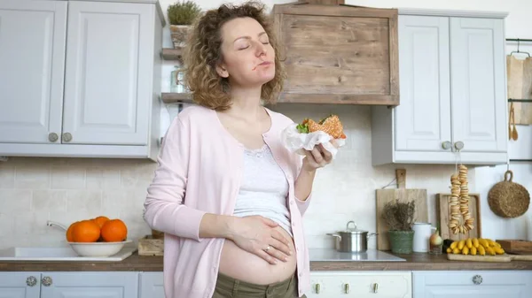 Ung gravid kvinna äter hamburgare. Ohälsosam mat under graviditeten konceptet. — Stockfoto