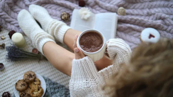Bir fincan sıcak çikolatayla yatakta bir kadın..