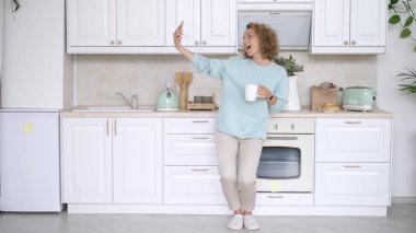 Sabah mutfakta cep telefonuyla selfie çeken bir kız.