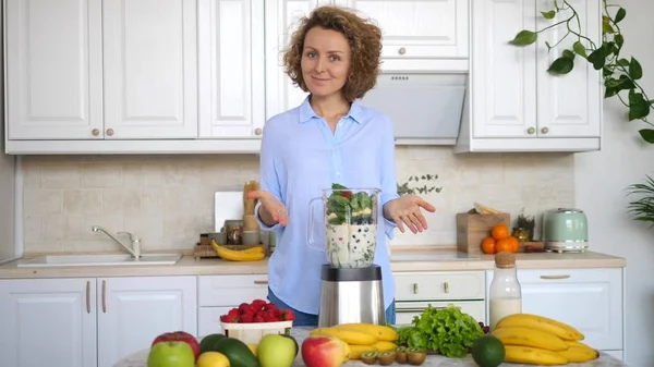 Giovane donna Preparazione Vegan Smoothie con i verdi in cucina — Foto Stock