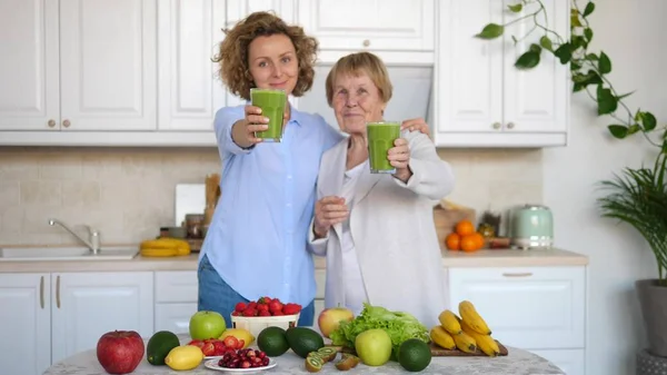Glad familj kvinnor med hälsosam smoothie i köket tittar på kameran. — Stockfoto