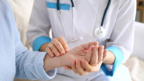 Doktor, yaşlı hastaların nabzını ölçüyor. Yakın çekim..