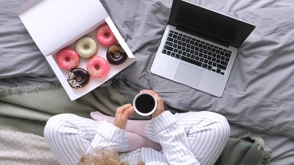 Pijamalı kadın bacakları, dizüstü bilgisayar, rahat yatakta kahvaltı.