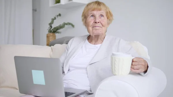Бабушка использует ноутбук дома — стоковое фото
