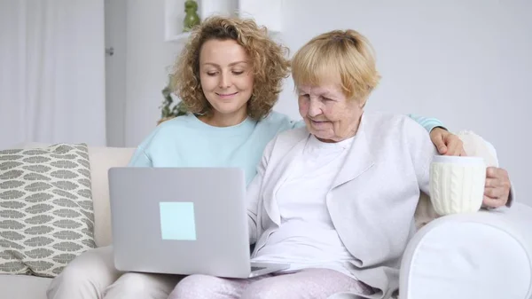 Внучка учит бабушку, как пользоваться ноутбуком дома — стоковое фото