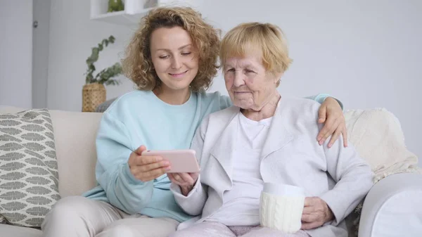 Nieta y abuela con teléfono celular en interiores — Foto de Stock