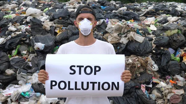 Man Activist In Mask Holding Stop Pollution Poster Standing At Garbage Dump