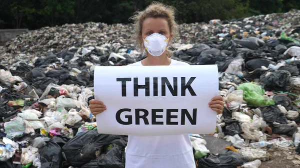 ゴミ捨て場で緑のポスターを考えている若い女性。過剰消費. — ストック写真
