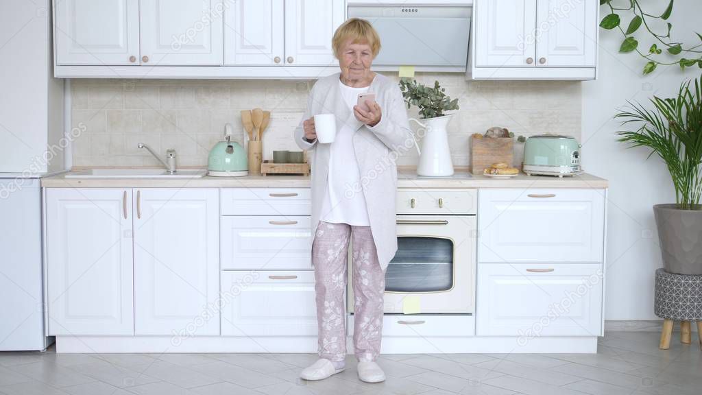 Cheerful Aged Woman Dancing In Kitchen With Smartphone