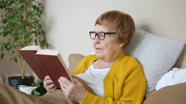 Femme âgée lisant un livre à la maison au lit — Photo