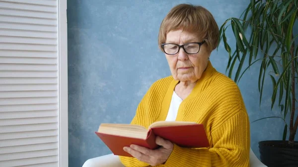 Grand-mère lisant un livre à la maison . — Photo