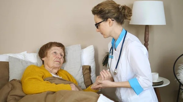 Doktor, yaşlı hastaların nabzını ölçüyor. Kadın hemşire ya da doktor yaşlı kadını evinde ziyaret etti. — Stok fotoğraf