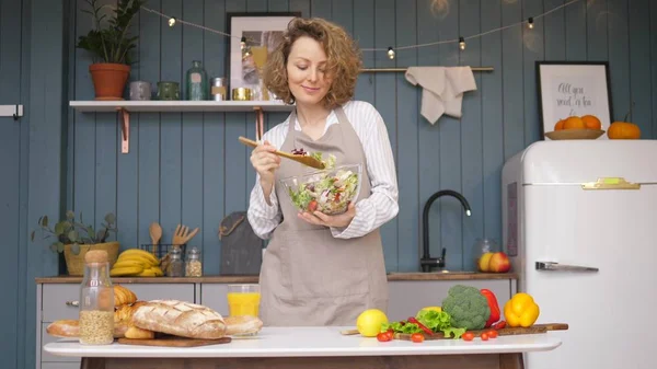 Mujer joven divirtiéndose mientras cocina ensalada saludable y bailando en la cocina —  Fotos de Stock