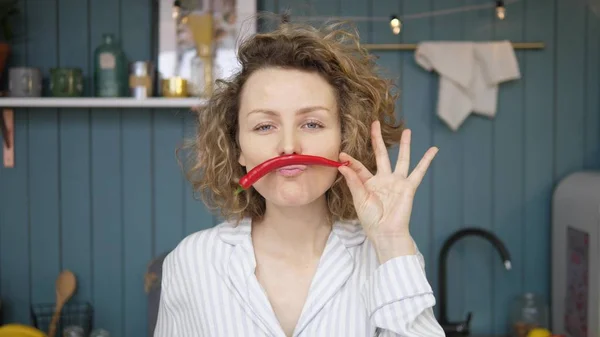 Mulher alegre fazendo bigode de pimentão pimenta na cozinha — Fotografia de Stock