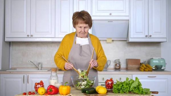 Senior kvinna matlagning sallad i köket. Hälsosam livsstil koncept. — Stockfoto