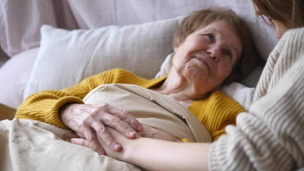 Familj, stöd, äldreomsorg, assistans, seniorkoncept. Mormor i sängen. — Stockfoto