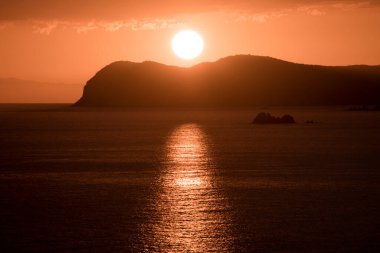 Gün batımında güneşin ufukta göründüğü deniz manzarası