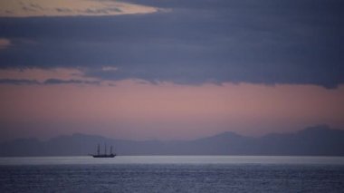 Gün batımında ufukta bir gemi olan deniz manzarası.