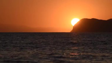 Güneşli deniz manzarası Elba Adası 'nda gün batımında dağın arkasında.