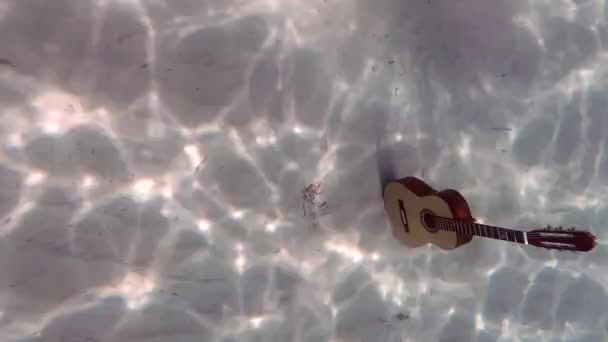上から見た砂の上に青い海の下にスペイン語のギター — ストック動画