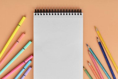 Libreta y marcadores sobre fondo pastel