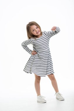 Beyaz arka planda sevimli, sevimli, uzun boylu bir gülüşü olan sevimli bir sarışın. Sıradan. İlginç bir duruş ve hareket. Kameraya bak ve gül. Metin için hızını kopyala.