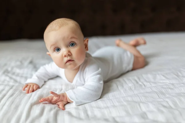 Bambino Carino Con Una Tuta Bianca Leggera Sul Letto Casa — Foto Stock