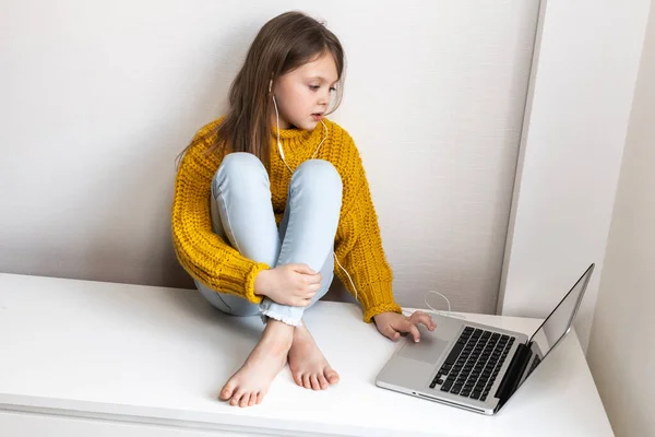 Schoolgirl student in home interior, online education during the quarantine. Online education and distance learning for kids. Home schooling. Distance education. Child using gadgets to study.