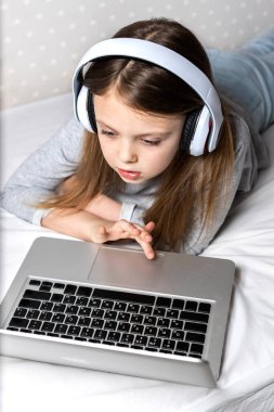 Evde eğitim ve çevrimiçi eğitim, uzaktan eğitim, evde eğitim, çevrimiçi öğrenim, çevrimiçi öğrenim. Genç bir kız, karantina sırasında bilgisayar kullanarak evdeki video bağlantısıyla iletişim kuruyor..