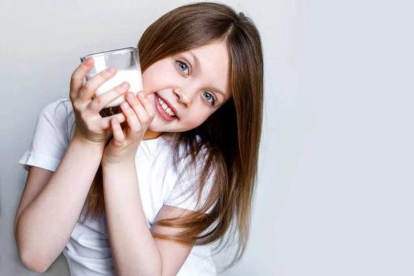 International milk day. The girl drinks white milk from a transparent glass. Products for human health. Healthy food. Baby a cup of with milk. World milk day. Copy space for text