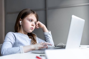 Sıkılmış genç kız. Öğrenmekten yoruldum. Liseli kız çevrimiçi çalışıyor, internette ödev yapıyor. Evde eğitim. Uzaktan eğitim. Bilgisayarın önünde bir çocuk. Çocuklar için çevrimiçi eğitim.