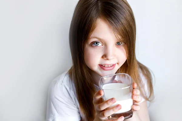 International milk day. The girl drinks white milk from a transparent glass. Products for human health. Healthy food. Baby a cup of with milk. World milk day. Copy space for text