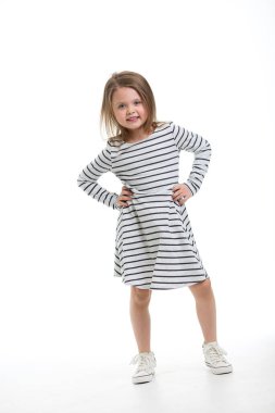 Beyaz bir arka planda duran sevimli, sevimli, sevimli, uzun boylu bir gülüşü olan küçük sarışın. Günlük kıyafetler. Kameraya bak. Metin için hızını kopyala.