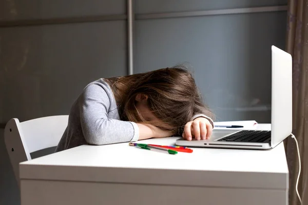 Laptopçu kızın masasında uyuyor. Uzaklardan gelen yorgun çocuk evde öğreniyor.
