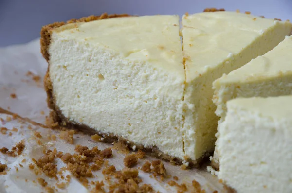 Fragrante cheesecake fatto in casa con base di cioccolato, tagliato a pezzi, sdraiato su uno sfondo leggero — Foto Stock