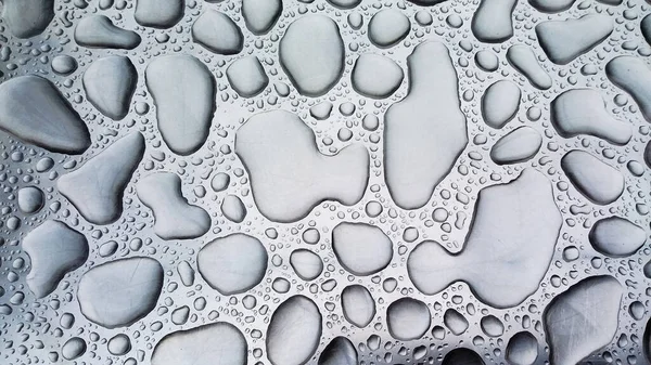 Grandes gotas de lluvia sobre una superficie de acero en color monocromo — Foto de Stock