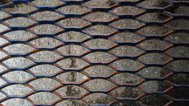 Elmas şeklinde delikleri olan paslı bir ızgara.