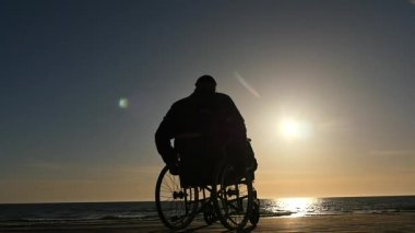 Deniz tarafı siluet yavaş hareket için tekerlekli sandalye hareket engelli adam