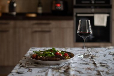 Evde biftek pişiriyorum. Mutfakta et kızartıyorum. Şık bir mutfak. Çok güzel hazırlanmış bir yemek. Masa takımı, kırmızı et şarabı..