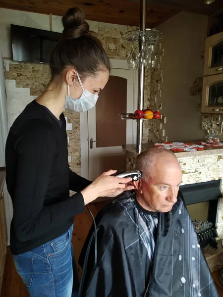 Une jeune fille coupe les cheveux de son père à la maison. Industrie des services pendant la quarantaine — Photo